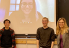 three graduate students in front of projector screen
