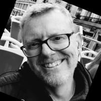 black and white photo of Derek Kreager, wearing glasses and smiling into the camera