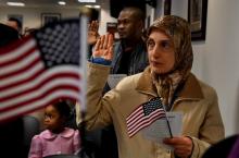 Muslim woman holding an American flag and raising her hand to take the citizenship oath