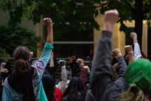 Protesters outside the Seattle West Precinct with their fists raised in the air
