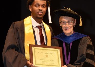 Ibrahim Burka receiving the Al Black Award from Judith Howard, Professor Emerita, at graduation 2024.