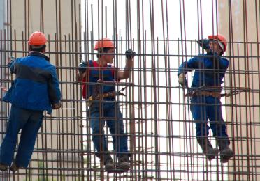 three construction workers perched on scaffold