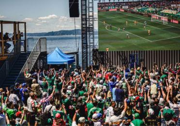 a crowd watches a World Cup match on a large screen at the Seattle Waterfront