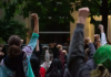 Protesters outside the Seattle West Precinct with their fists raised in the air